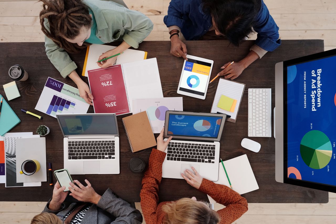 Une équipe variée travaille ensemble sur des stratégies de marketing digital autour d’un bureau, avec des ordinateurs portables et des tablettes.